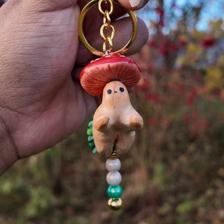 Handschlüsselanhänger in Form eines Pilzes mit rotem Hut und bunten Perlen.